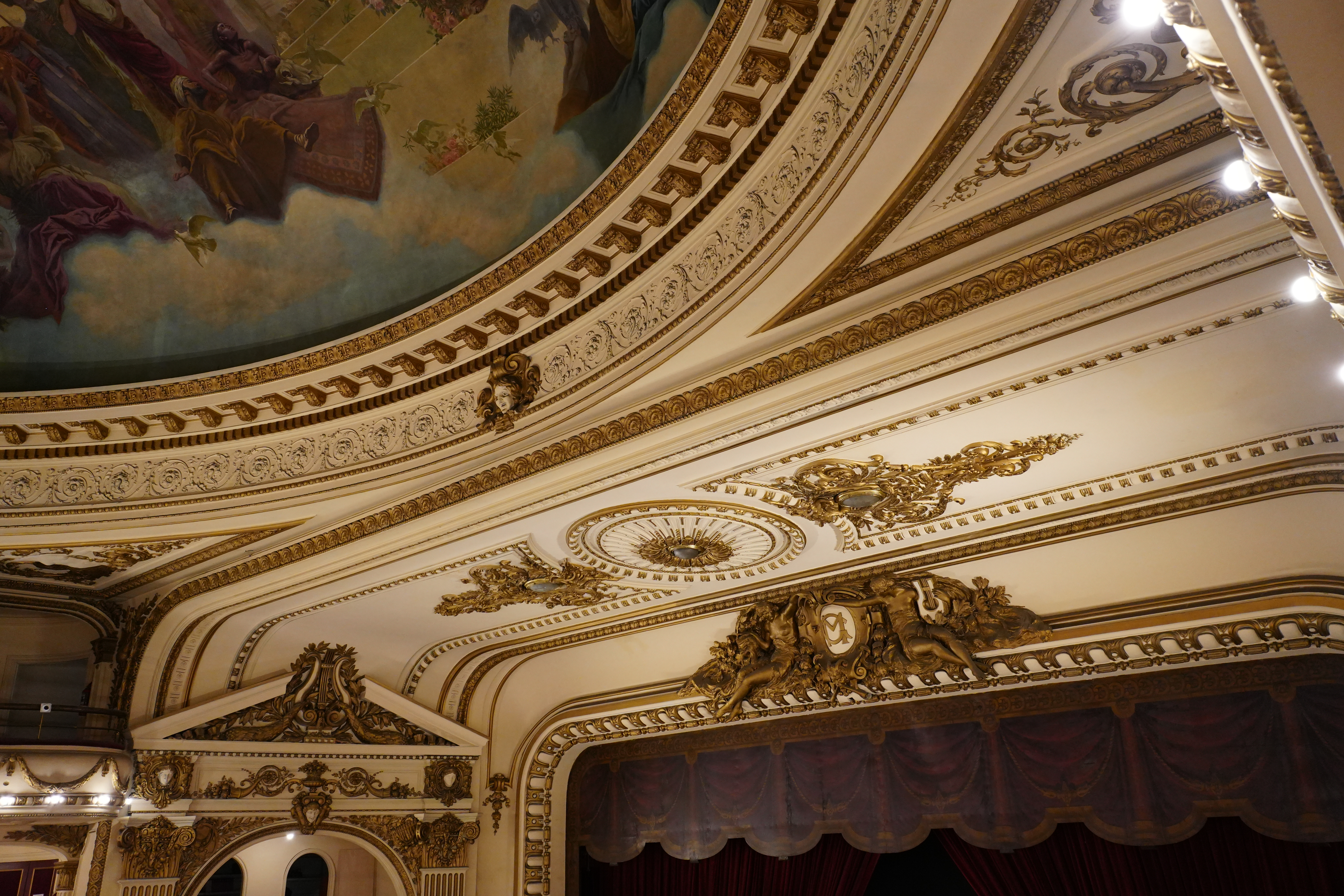 Close-up of ornate gold and white ceiling molding and mural.