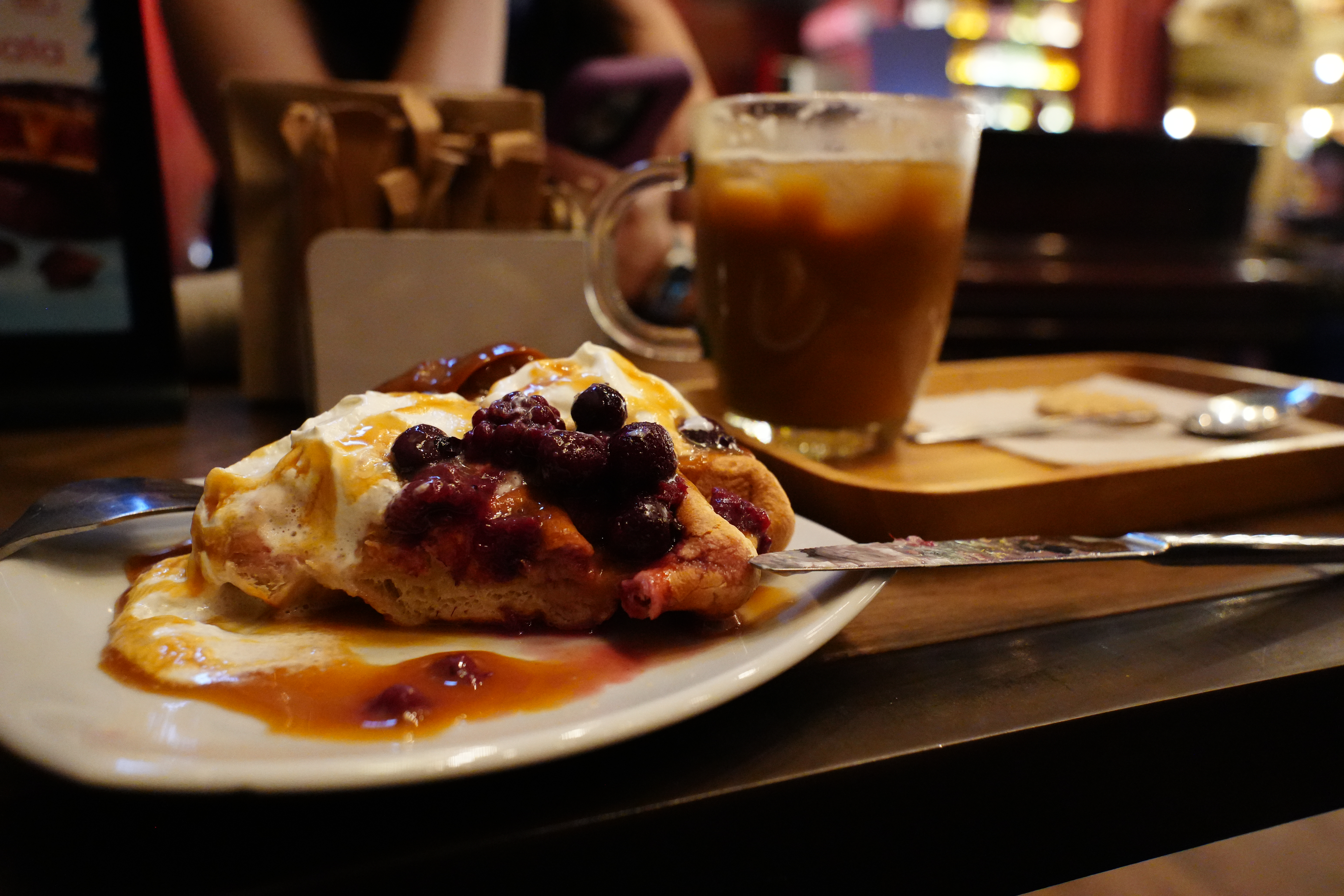 Close-up of berry-covered waffle with iced coffee.