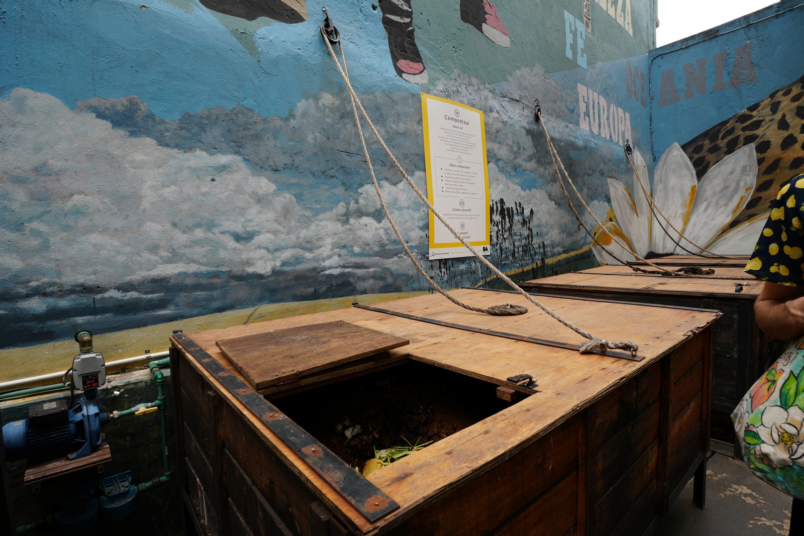Wooden compost bin with instructions beside it