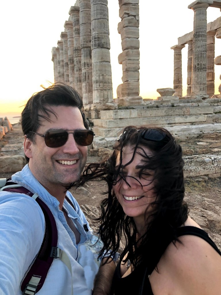Couple taking a windswept selfie at the Temple of Poseidon during sunset