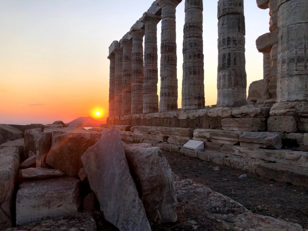 Sun setting on the horizon beside the Temple of Poseidon, Cape Sounion