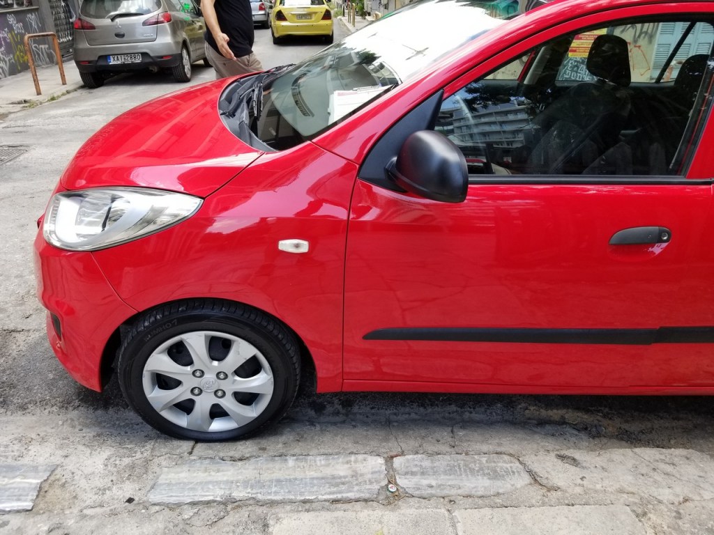 Red rental car parked on the road near Cape Sounion
